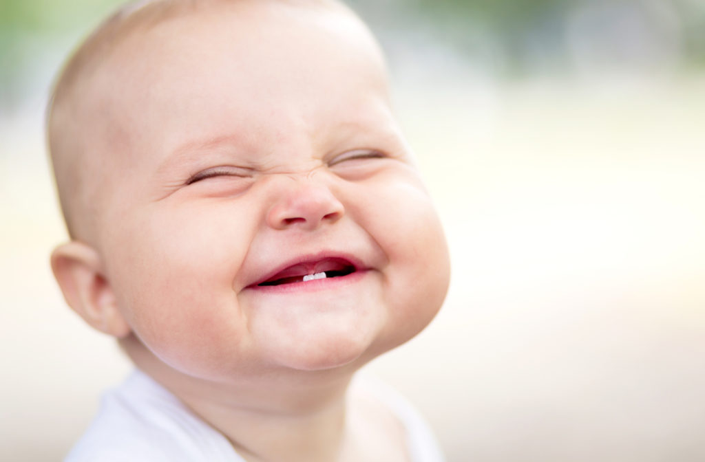 Adorable smiling baby with 2 front teeth and a gummy smile.
