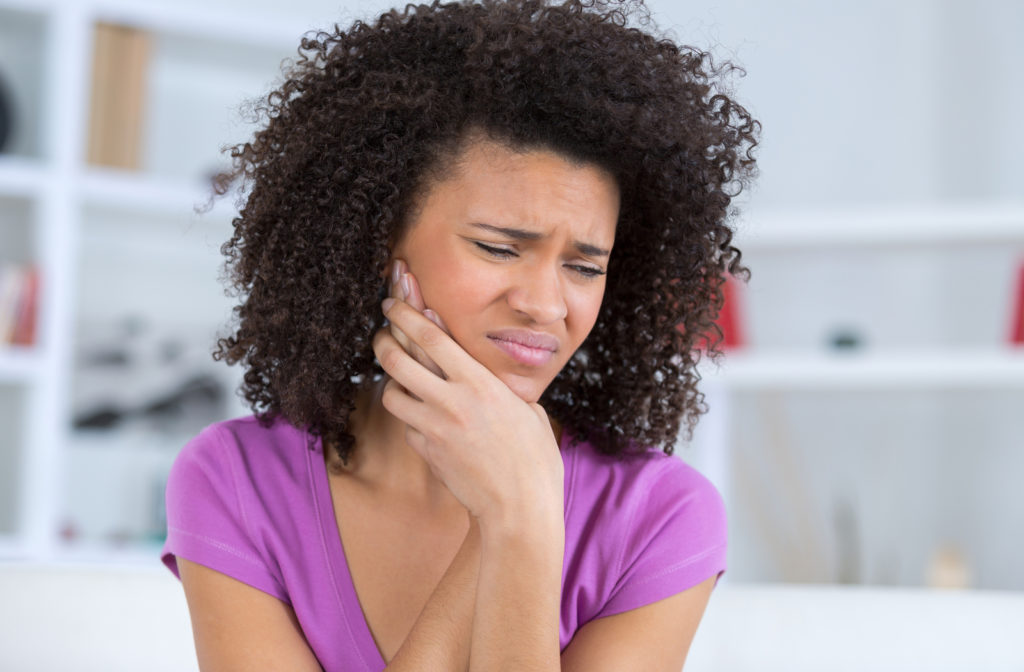 Young adult touching jaw because of wisdom tooth pain