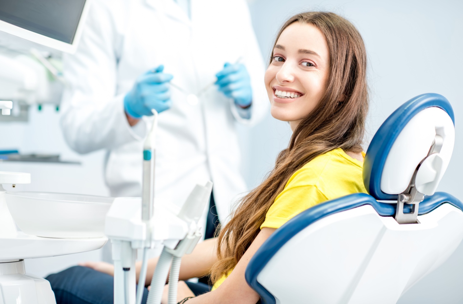 A relaxed patient sits comfortably in a dentist's chair, ready for teeth cleaning.