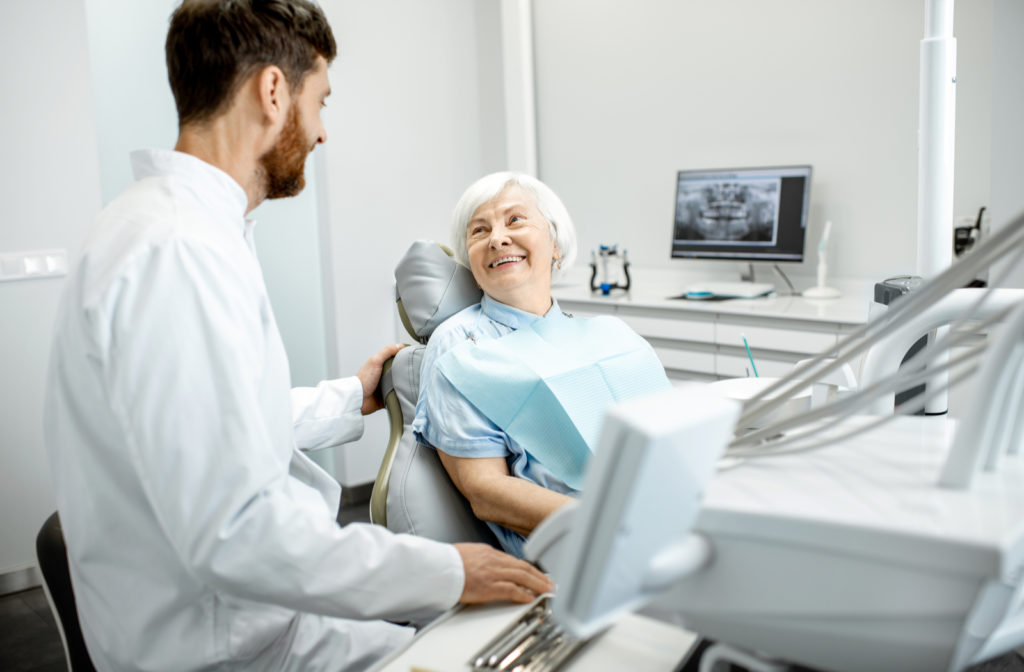 Dentist talking to happy elder patient during her dental exam consulting about dental implants
