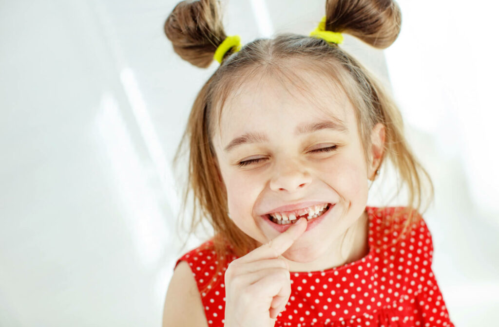 a young girl points at her missing front tooth