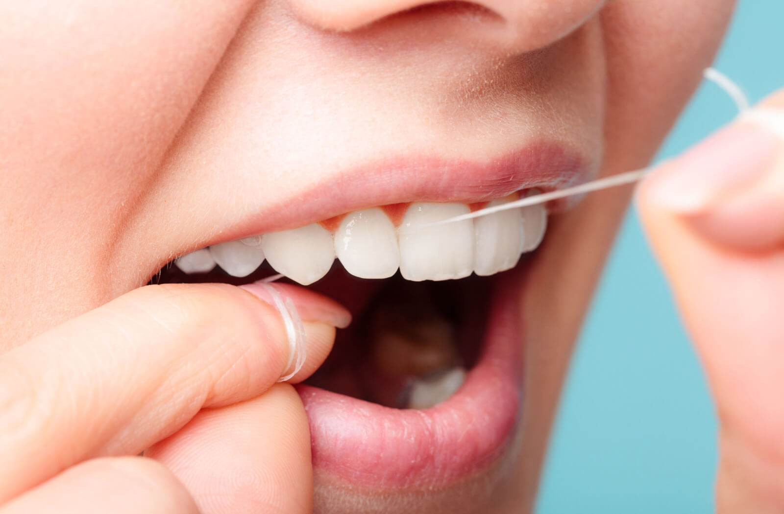 A close-up of a woman flossing her beautiful teeth.