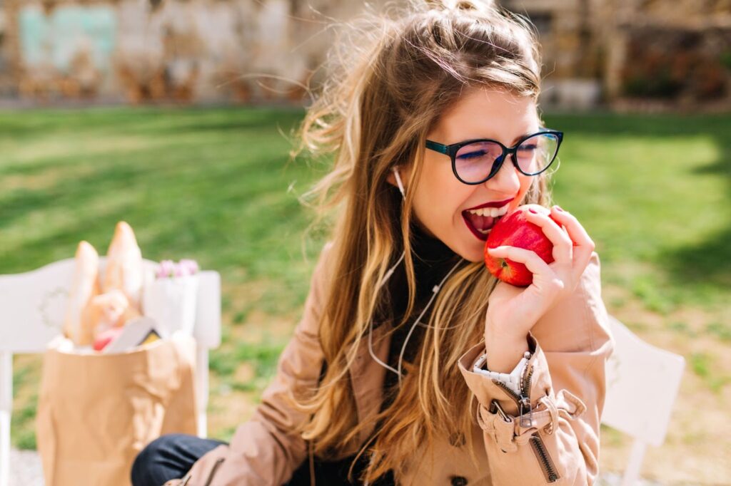 A woman enjoys an apple for a snack, supporting strong teeth and gums.