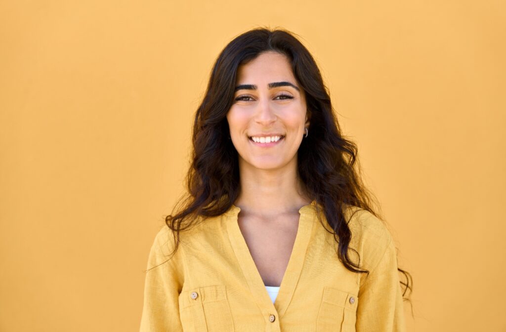A woman smiling confidently with her teeth showing after a root canal treatment.