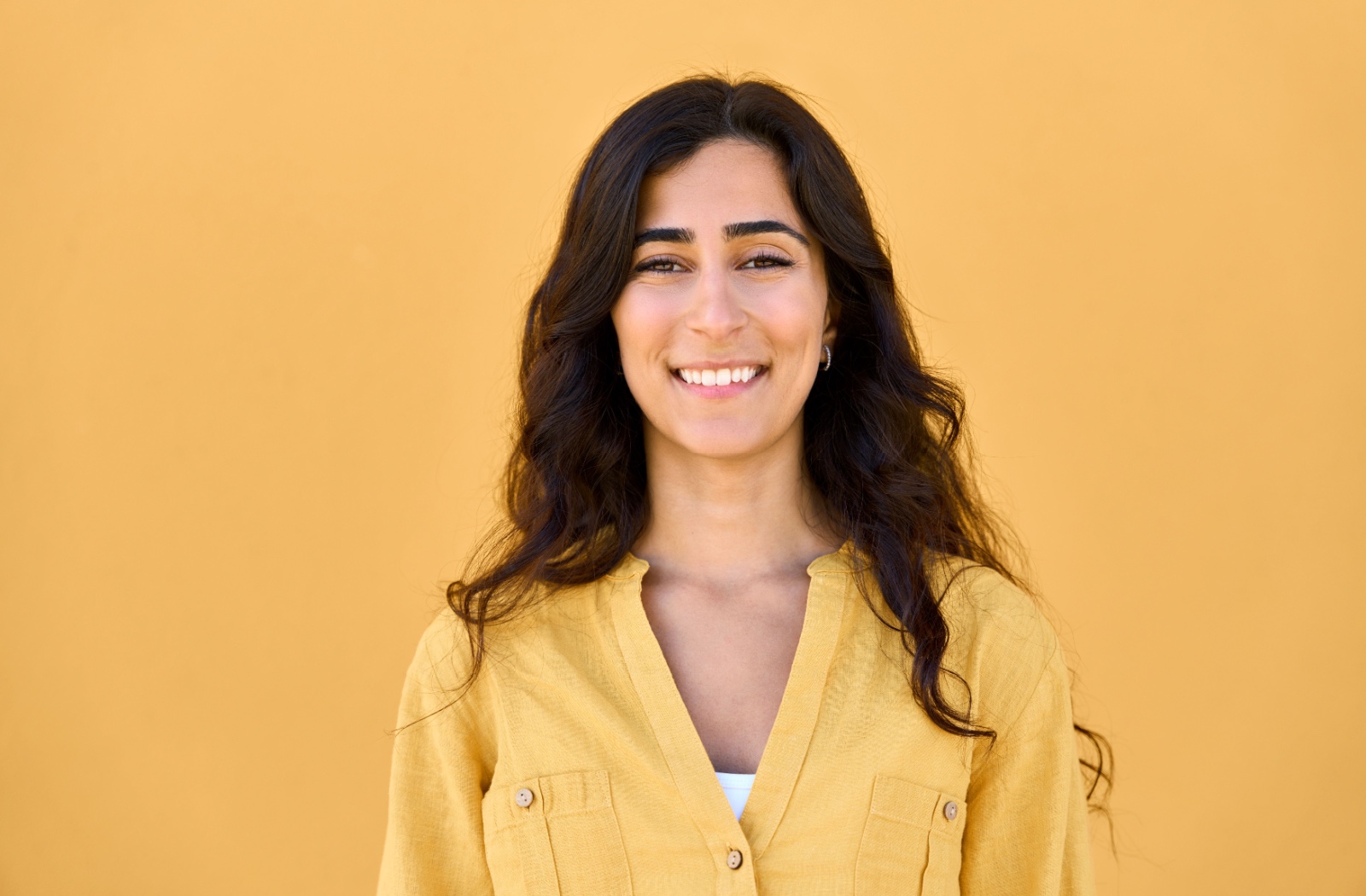 A woman smiling confidently with her teeth showing after a root canal treatment.