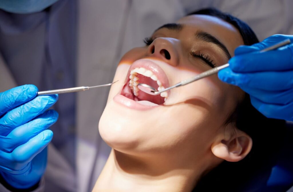 Woman receiving a professional dental cleaning from a dentist using specialized tools to remove plaque and tartar.
