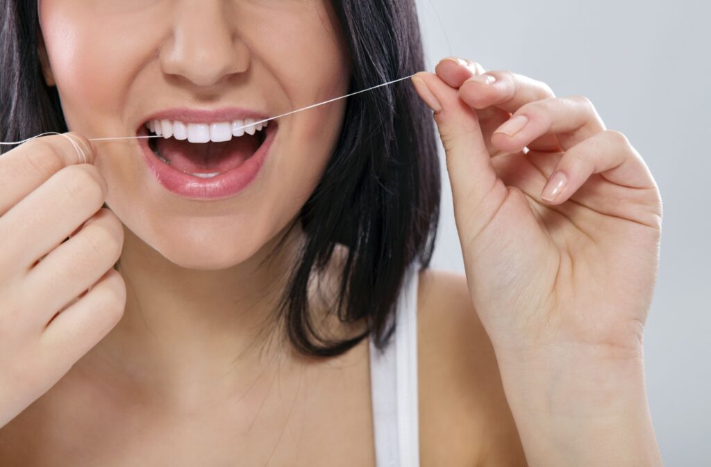 Up close image of woman flossing her upper front teeth.