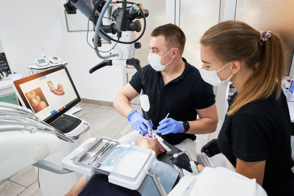 A dentist and assistant using an intraoral scanner on a patient.